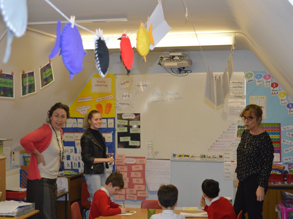 three teachers standing up at the front of a class