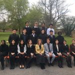 A range of students and teachers sat in a row